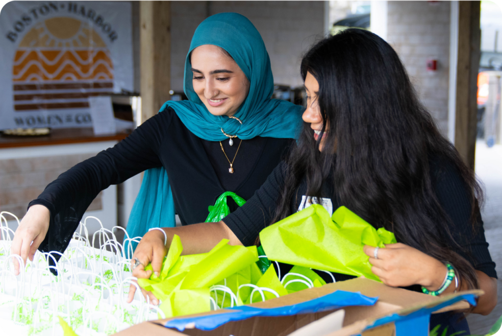 Two people filling out gift bags.