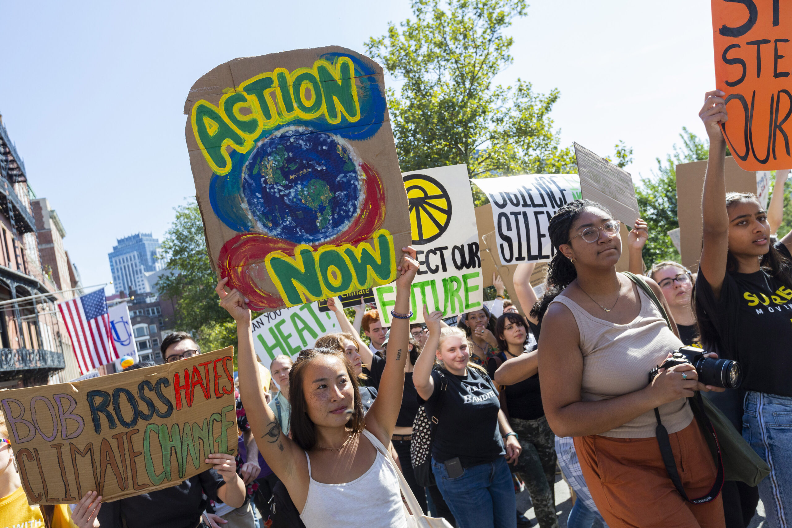 A crowd of young people holding brightly colored signs urging action on climate change.