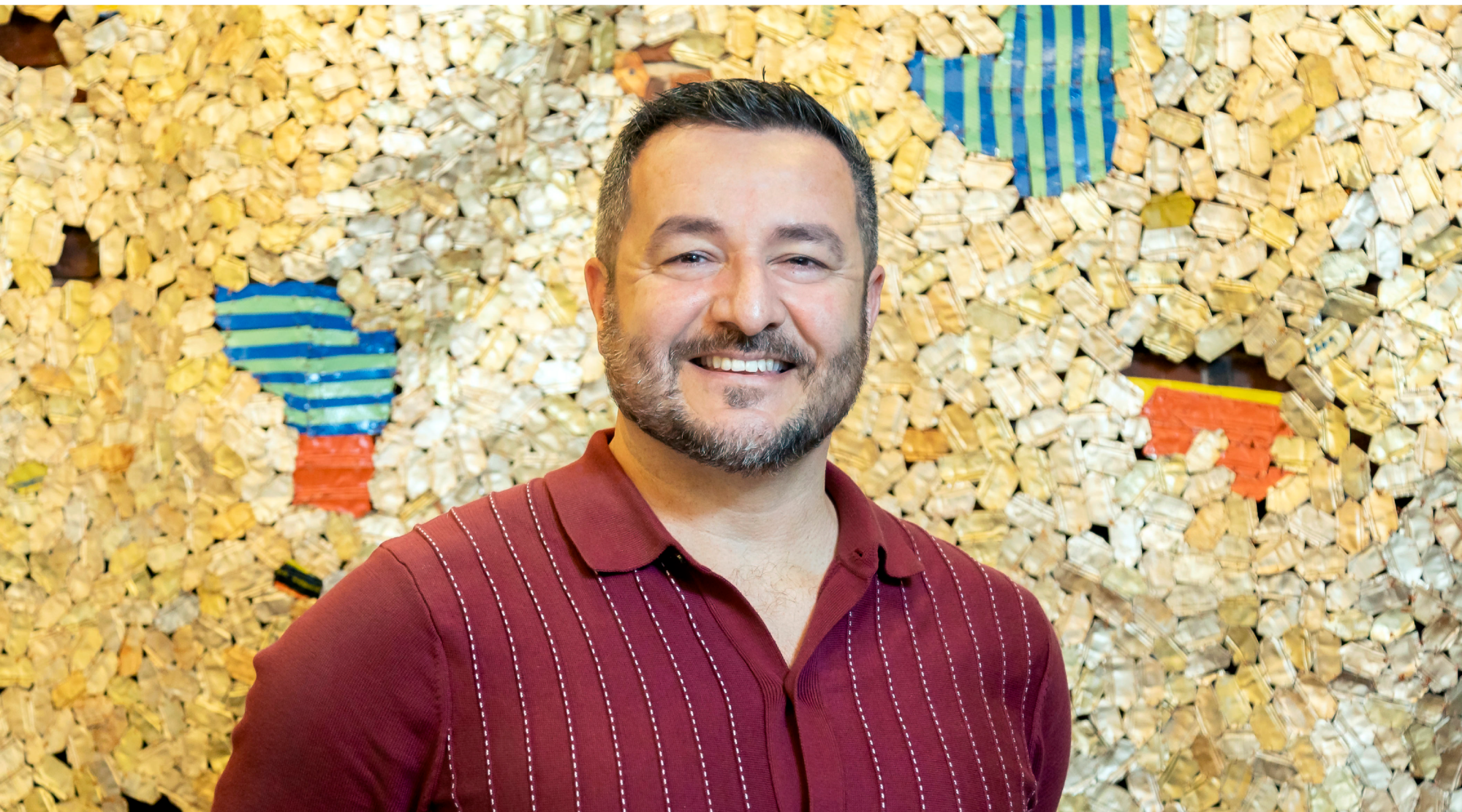 Francisco Torres poses for a headshot. He wears a red button down and smiles warmly.
