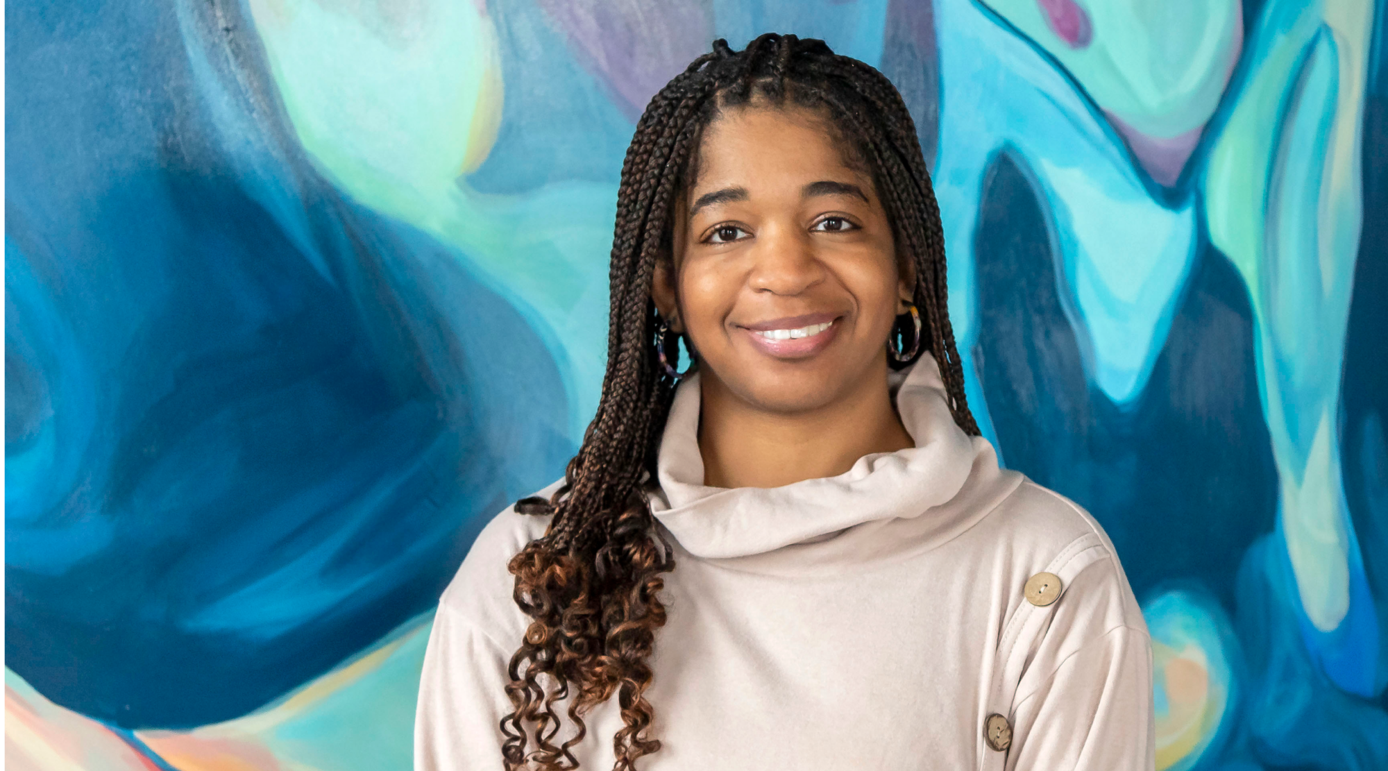 Kathryn Wright poses for a headshot. She has long braids and smiles warmly.