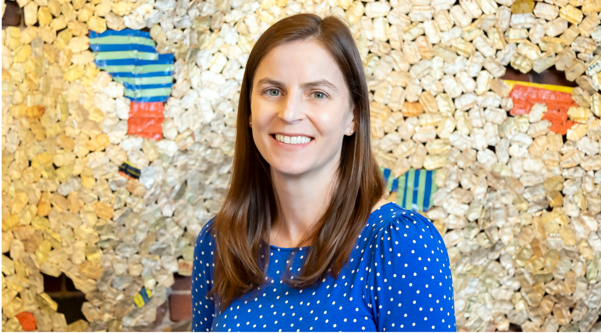 Mary Chalifour poses for a headshot. She wears a blue and white polka dot top and smiles warmly.