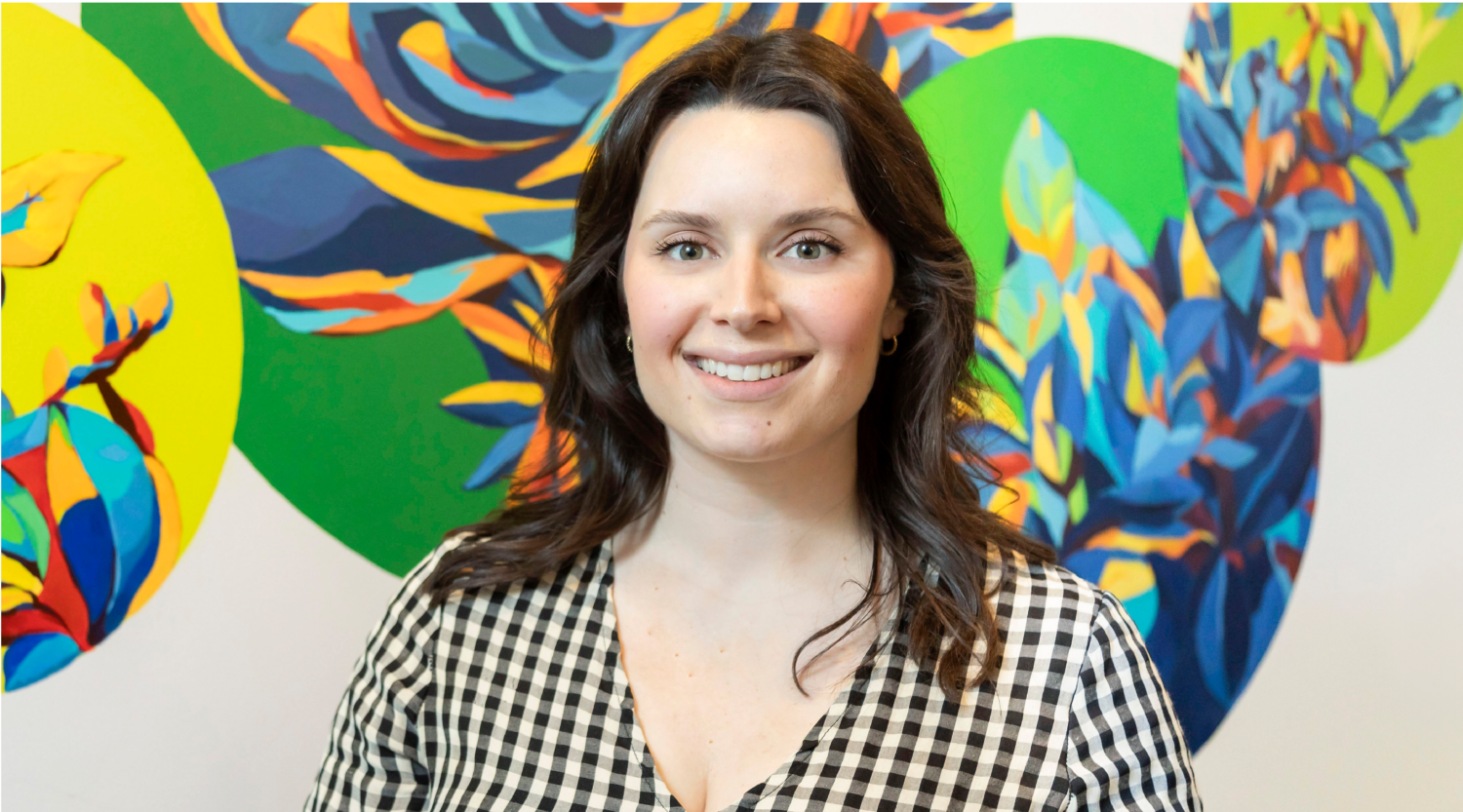 Maryam Greene poses for a headshot. She has brown hair and smiles warmly.