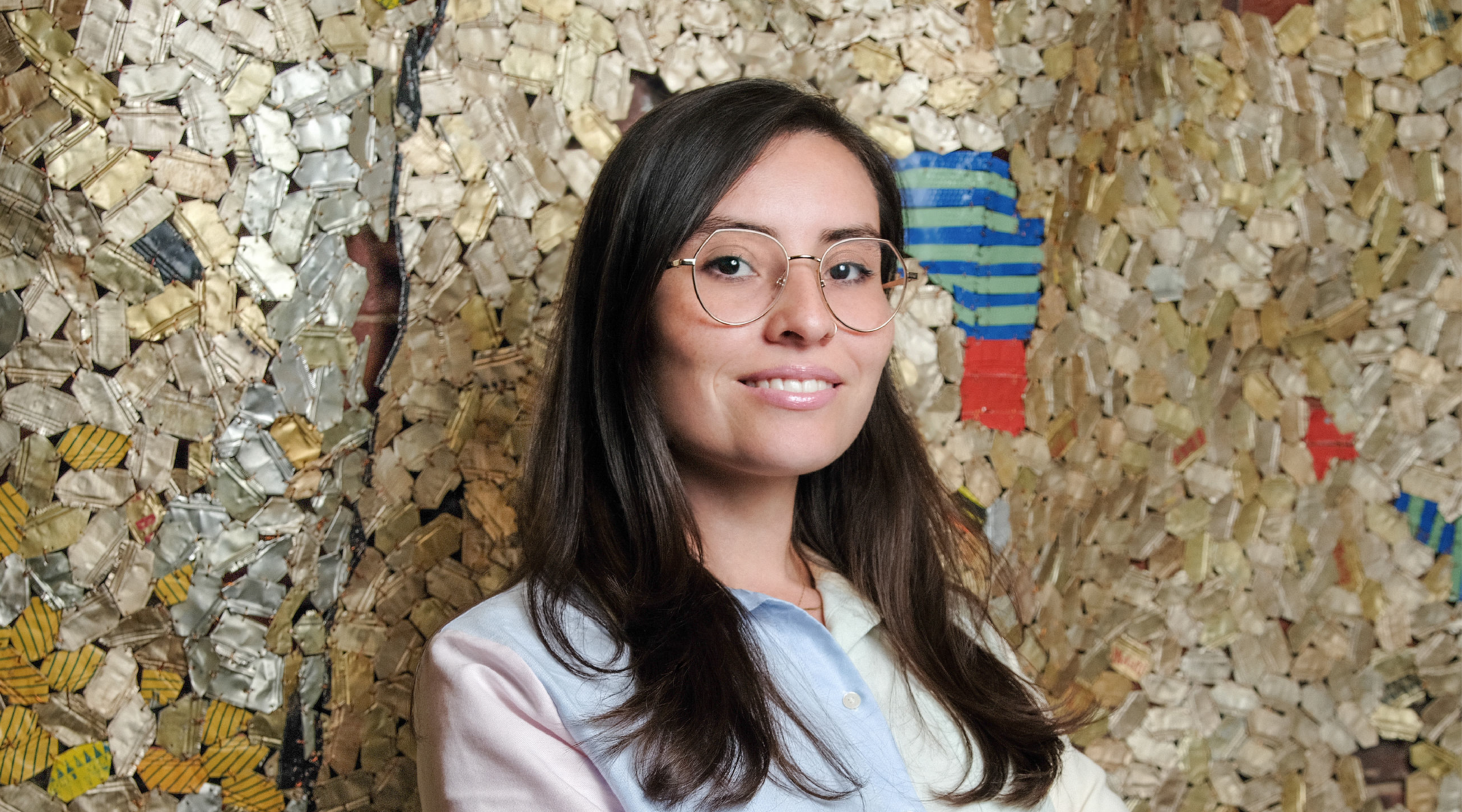 Susana Reyes poses for a headshot. She wears a multicolored top and glasses. She smiles.