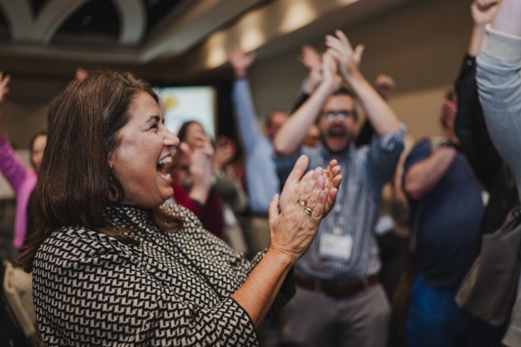 A group of arts grantees cheer and clap together.