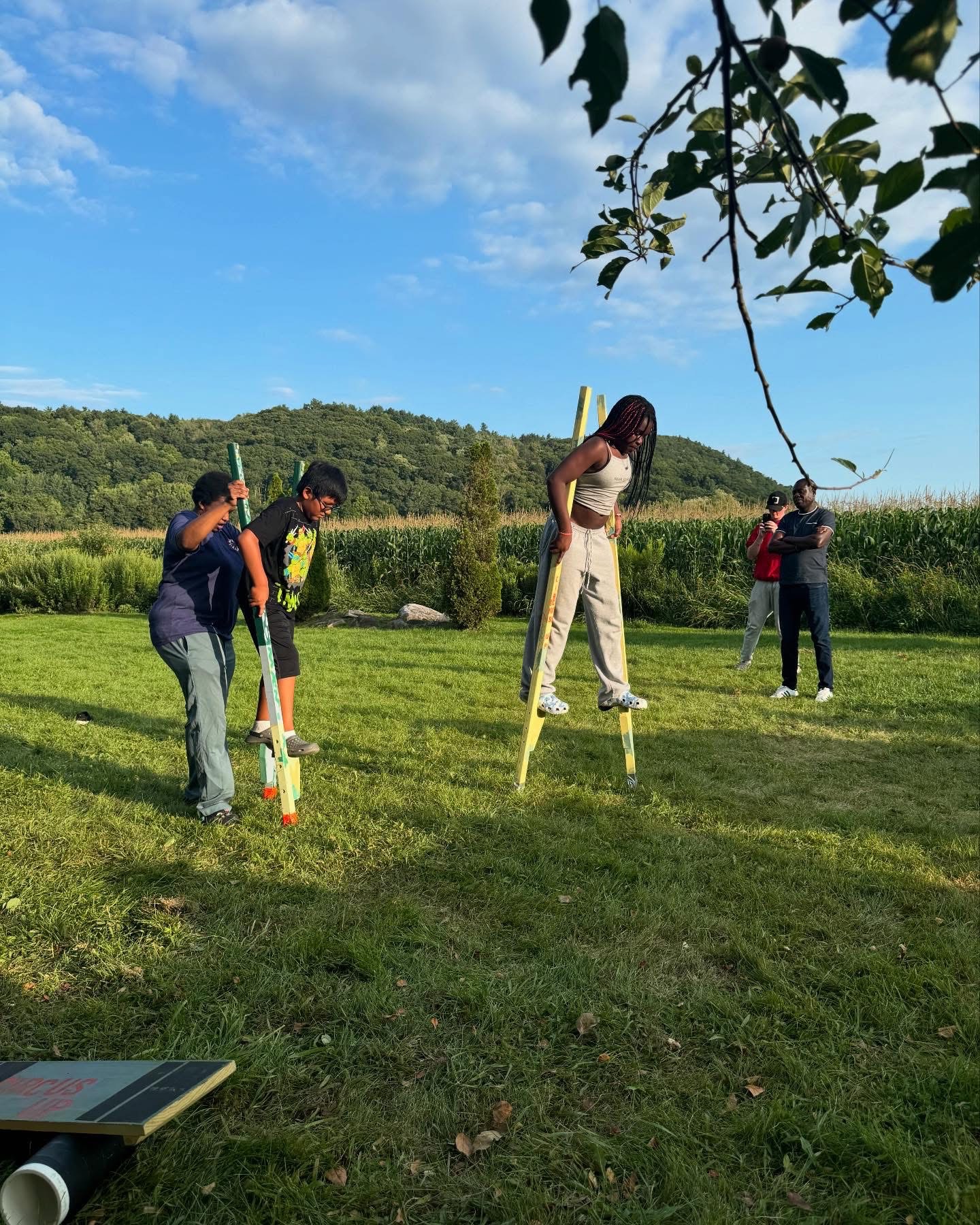 Students stand in a field and learn to walk on stilts as part of a youth development program.