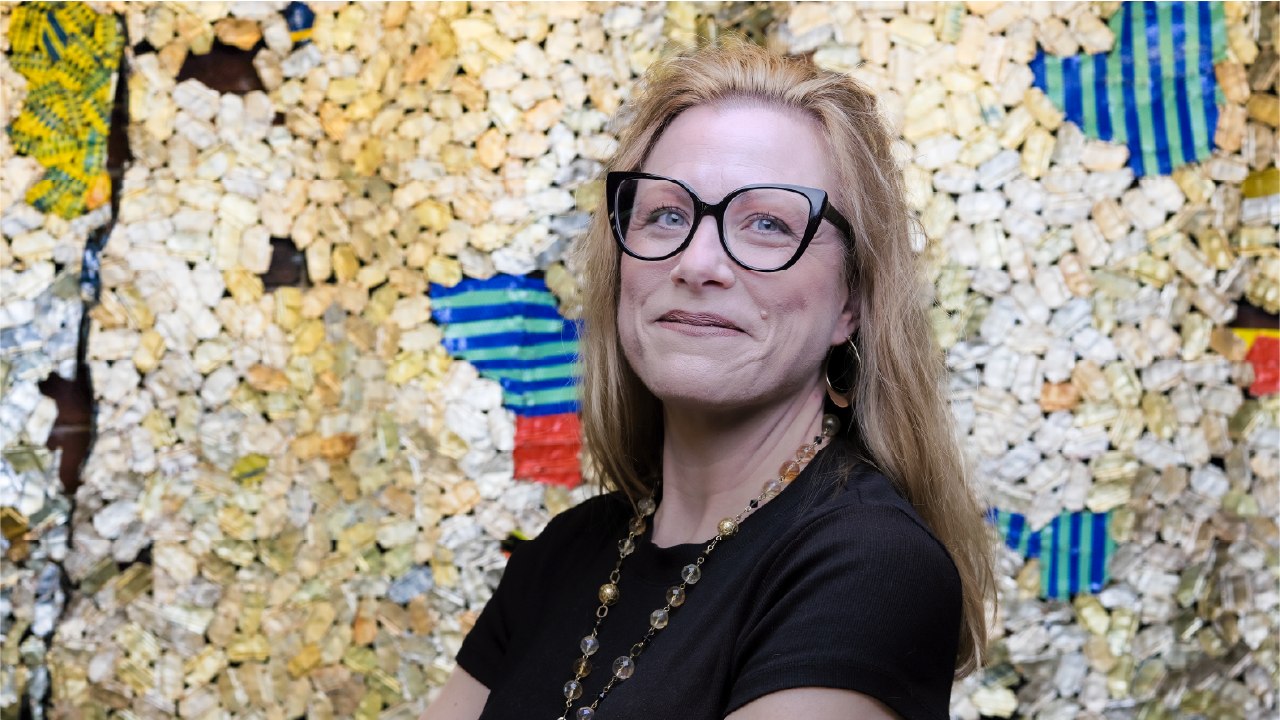 Kerri Hurley wears black glasses and a black top. She has blonde hair and smiles.