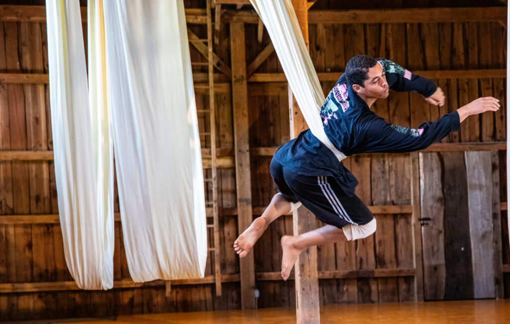 A performer rehearses choreography on white silks