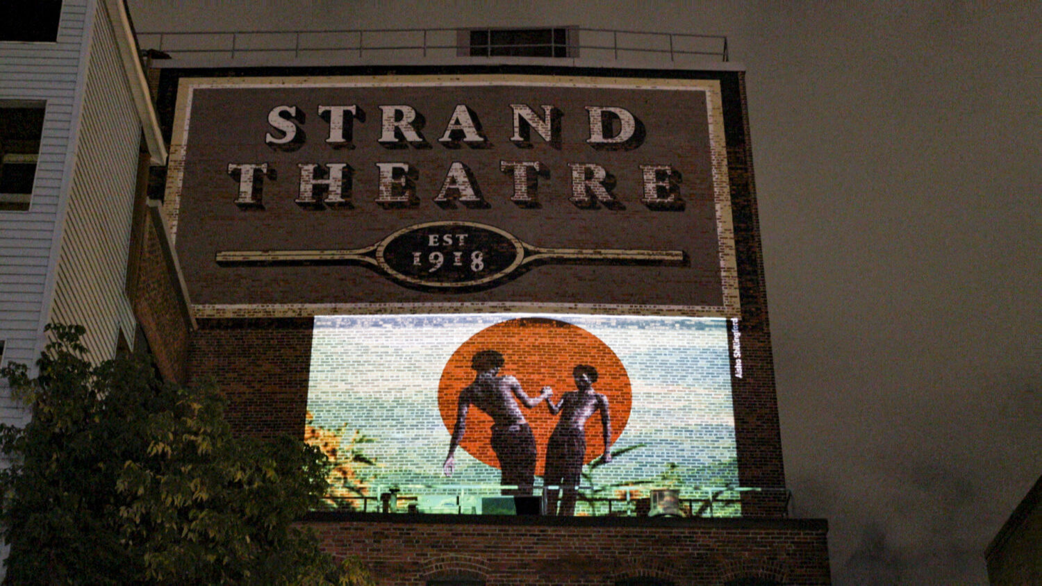 An artwork is projected on the façade of the Strand Theatre.