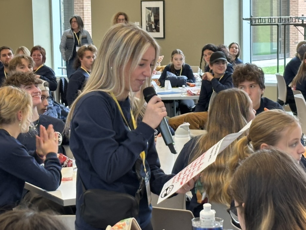 A high school student stands with a microphone sharing ideas at a student summit at Mohawk Trail school.